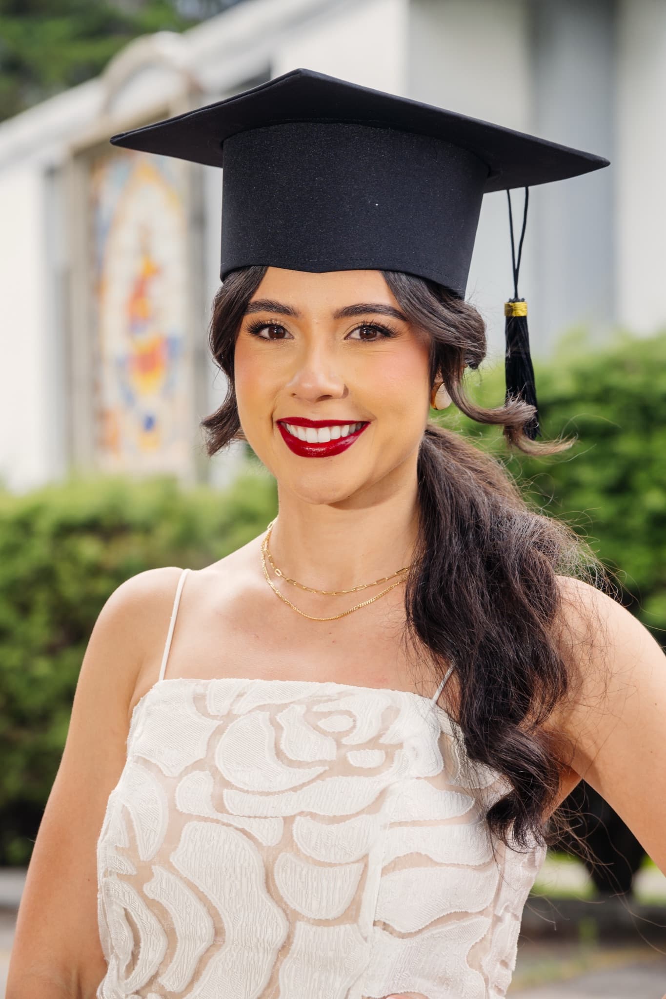 Primer plano de graduada con vestido blanco y birrete