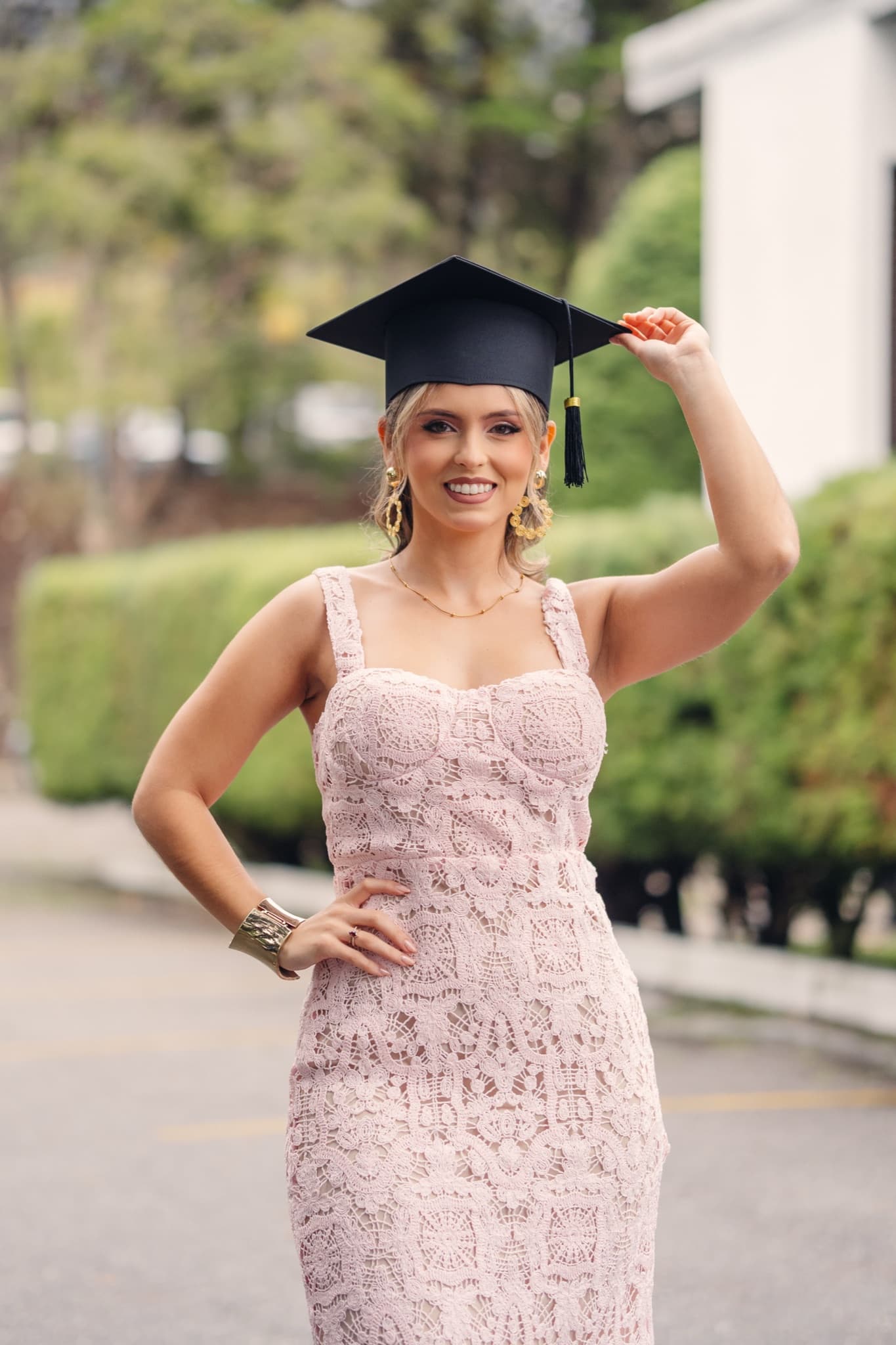 Graduada con vestido rosa y birrete en un retrato de exteriores