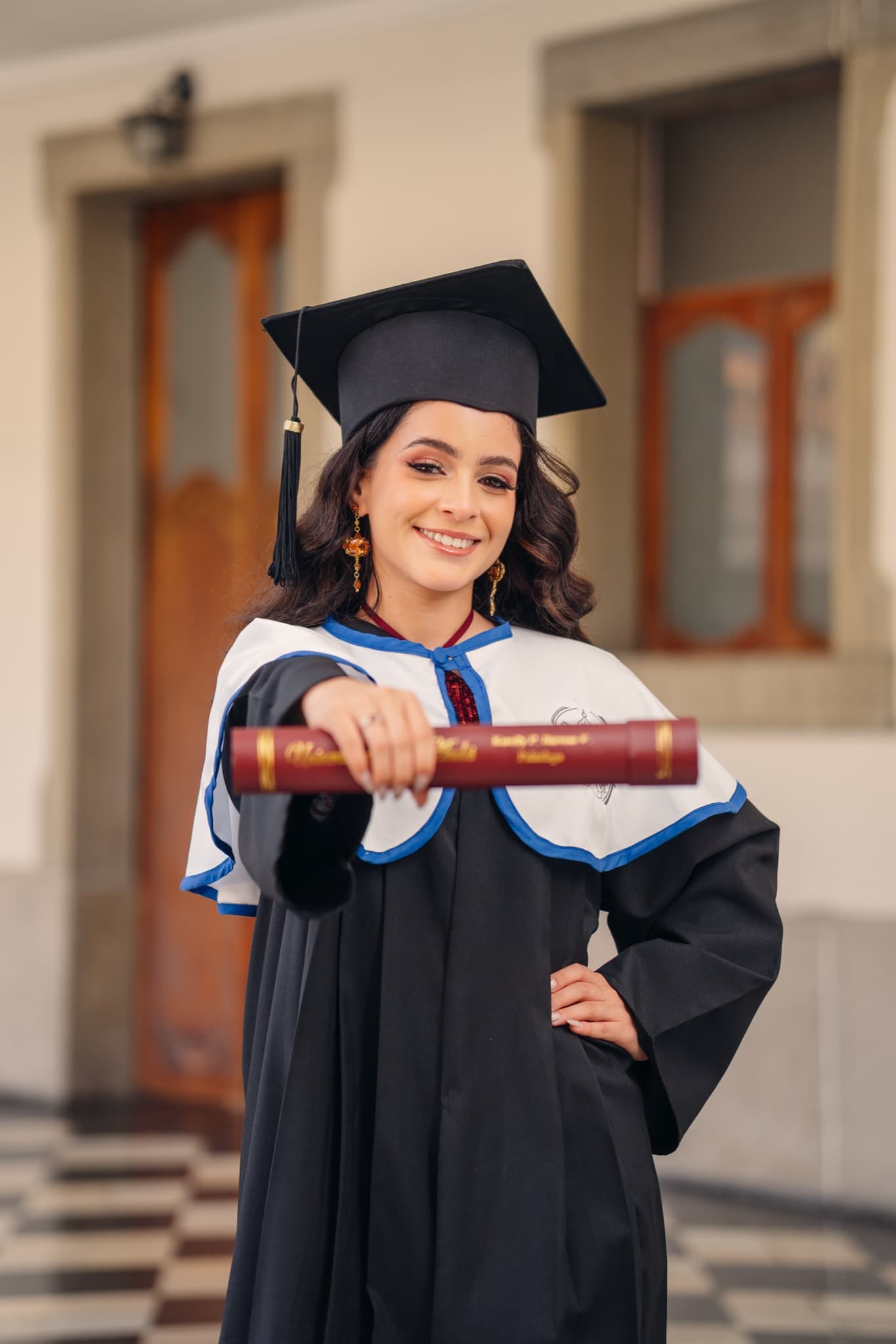 Graduada con toga mostrando su diploma frente a la cámara