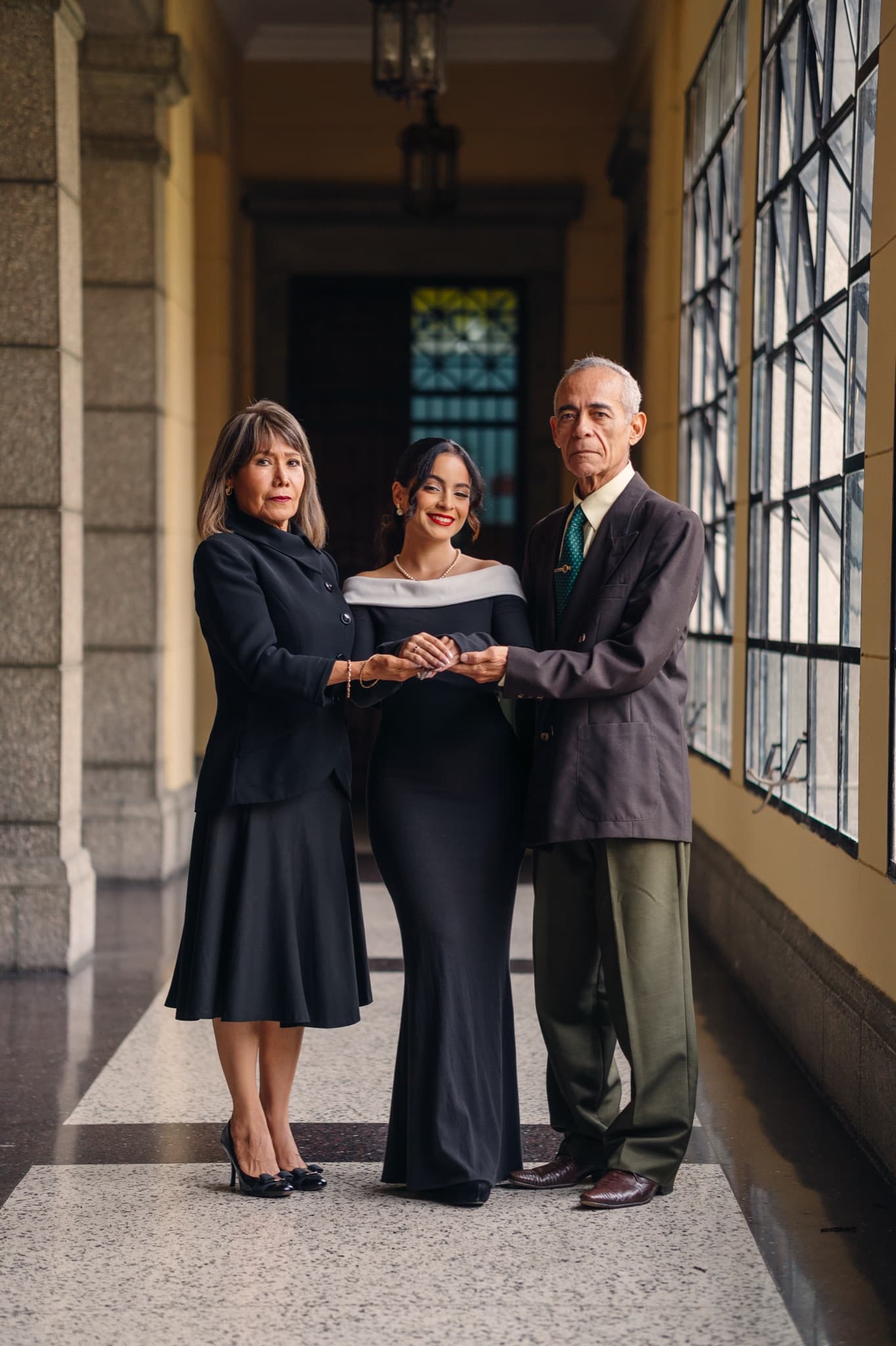 Graduada retratada con sus padres en una locación institucional