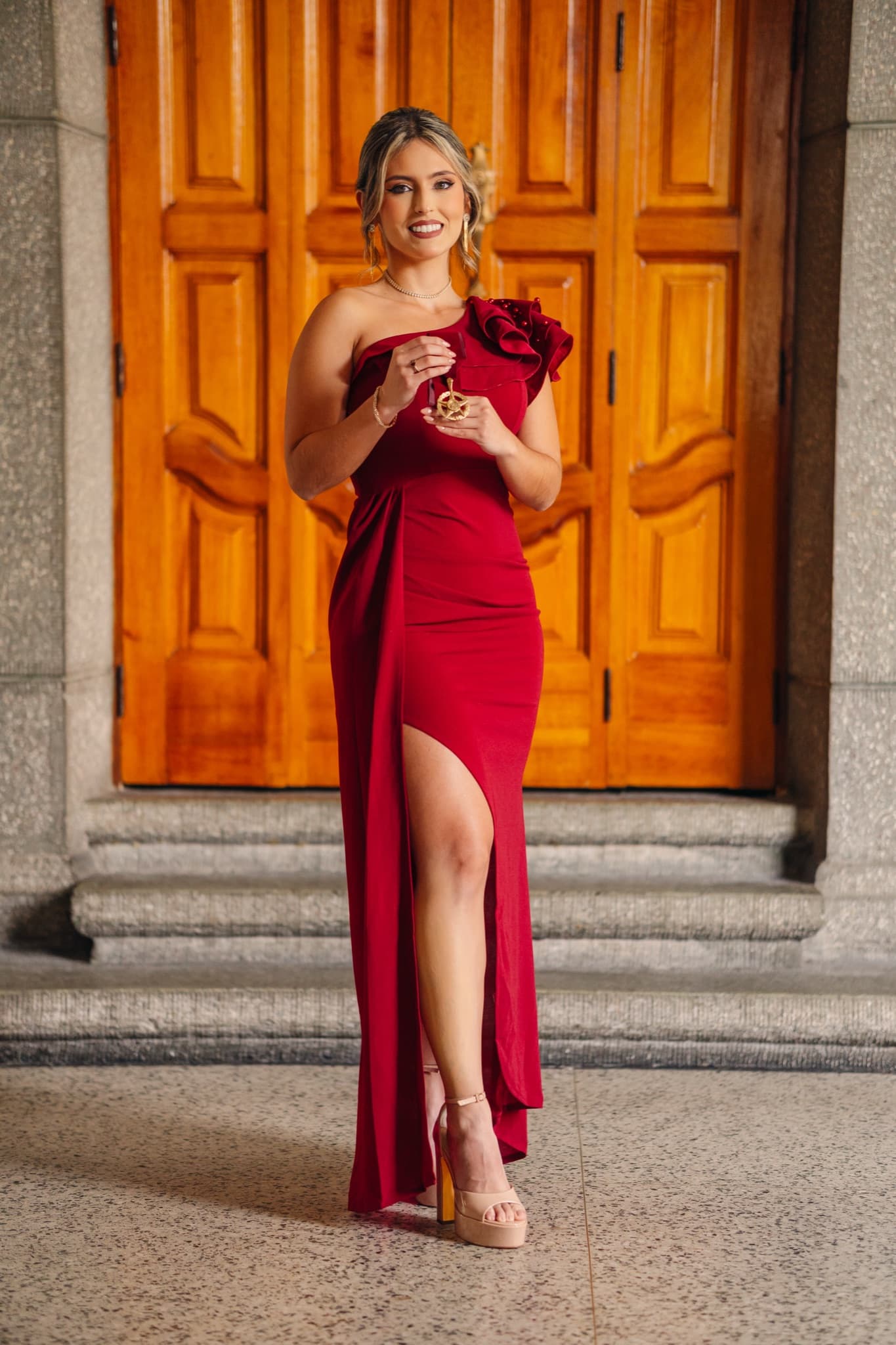 Graduada con vestido rojo mostrando su medalla