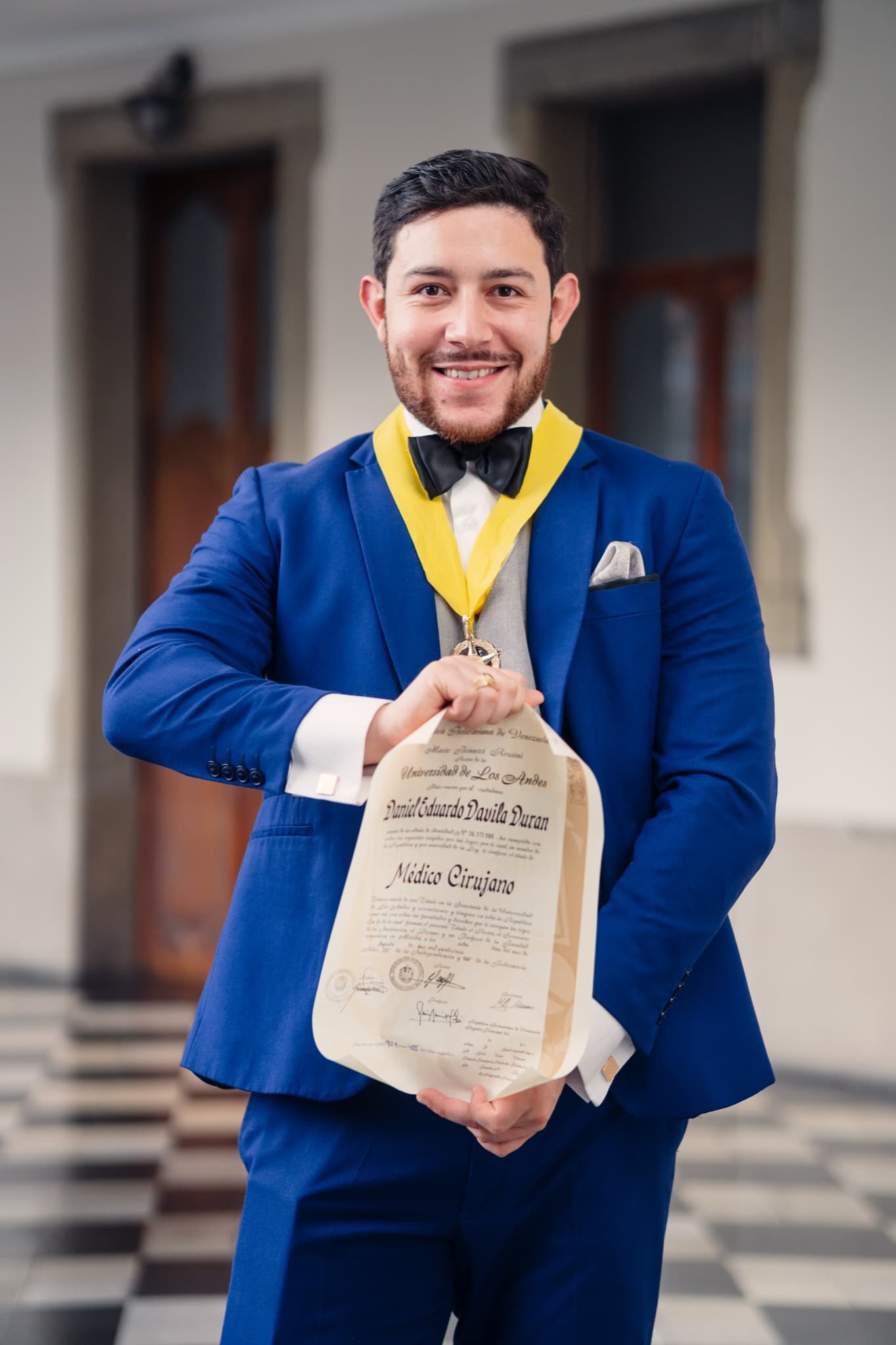 Graduado con traje azul mostrando su diploma universitario